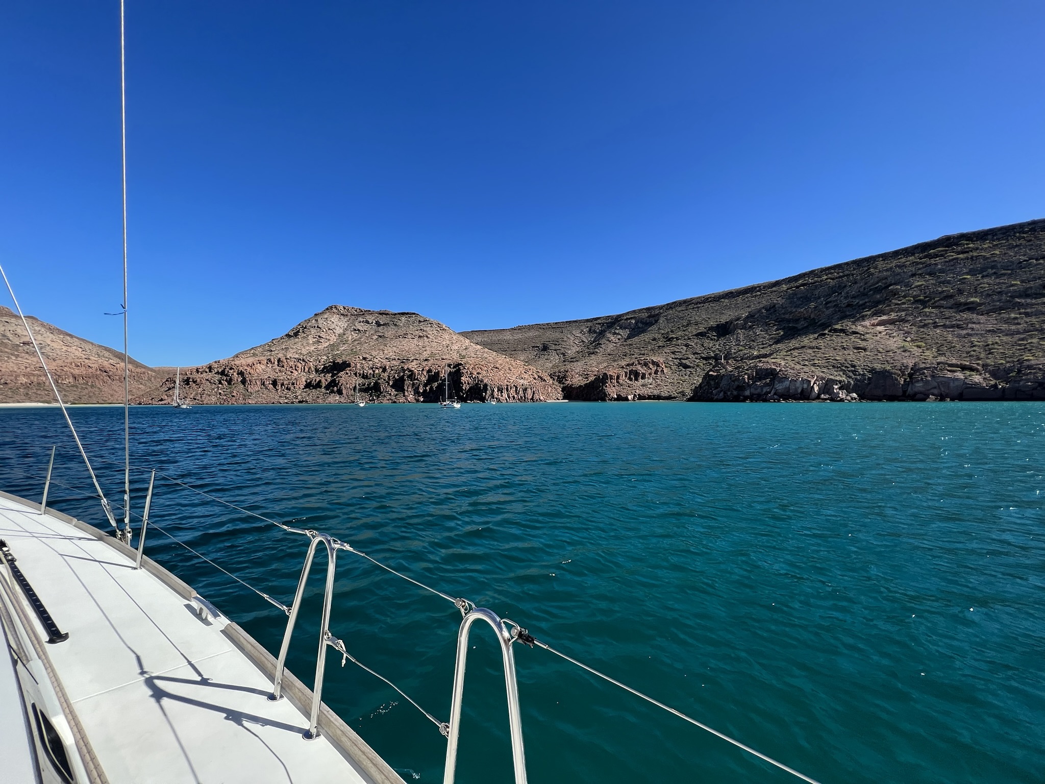 Sailboats anchored beneath the desert cliffs of the Sea of Cortez