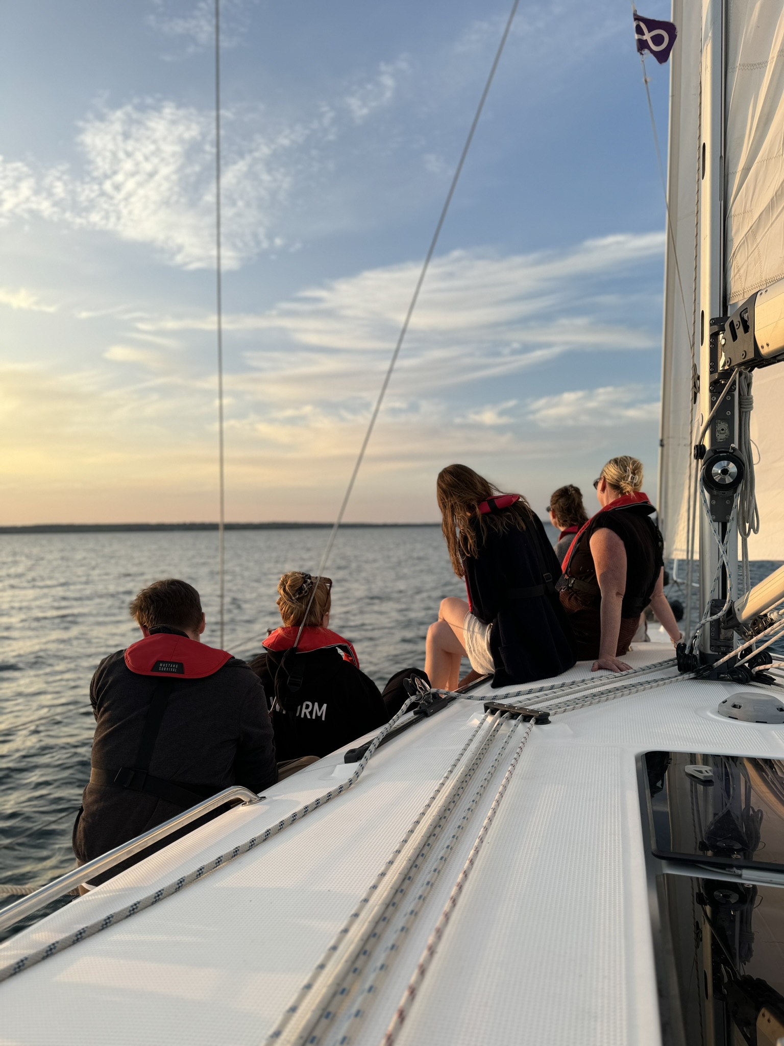 Sailors watching the sunset from the foredeck on Lake Ontario